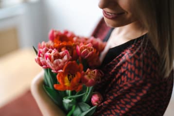 A woman holdin a bunch of red tulips